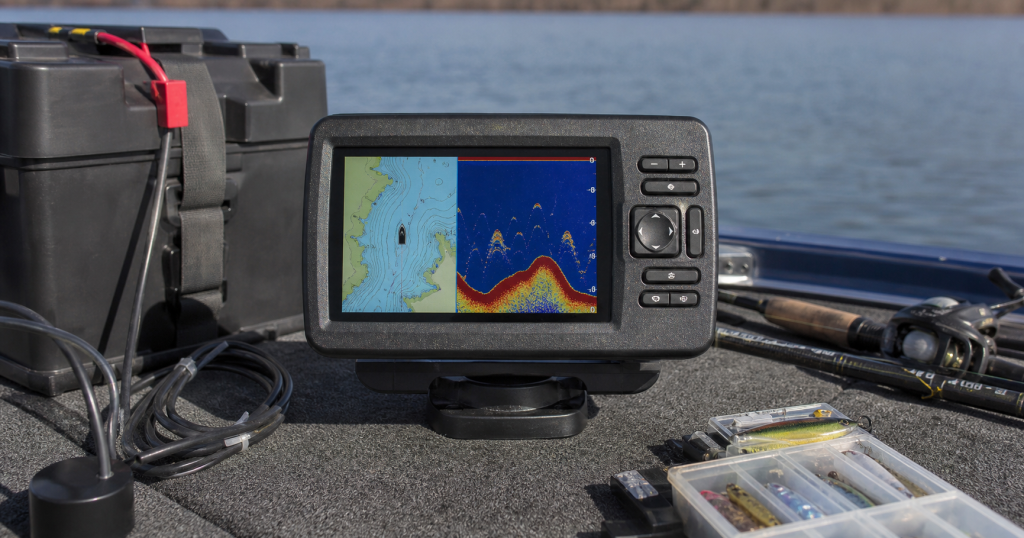 Mid-size fish finder with battery box and transducer cable arranged on a fishing boat deck