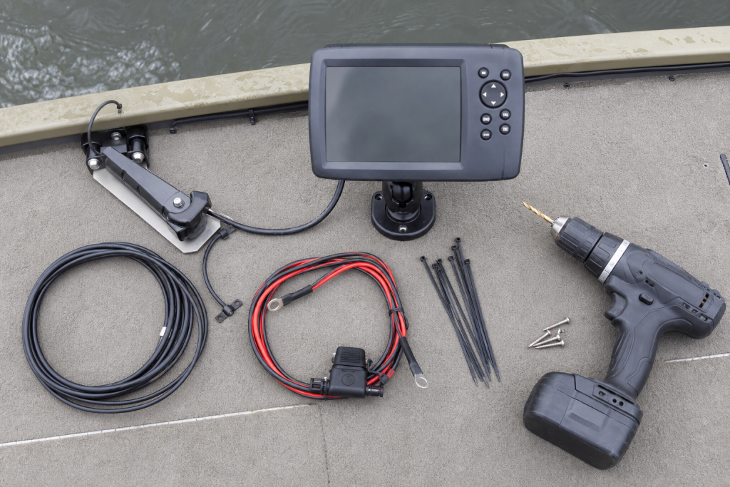 Fish finder wiring, mounting hardware, and install tools on a boat deck